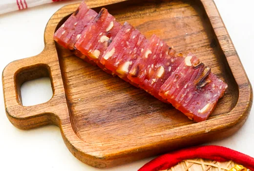 Sliced halwa studded with nuts on a wooden tray