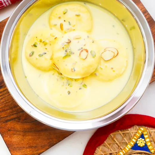 Rasmalai in creamy milk topped with pistachio and sliced almonds