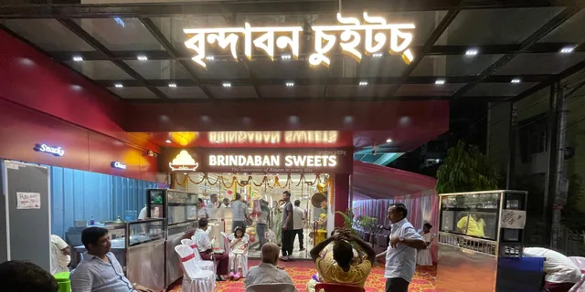 The Brindaban Sweets shopfront at night, signage lit in Assamese and English